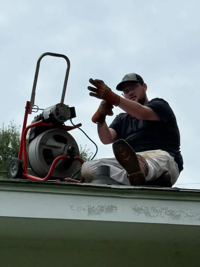 Paul operating a drum drain machine on a trailer, cable feeding out toward the work