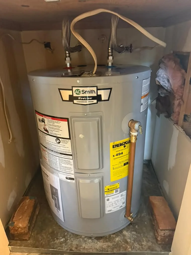 An A.O. Smith electric water heater in a wooden closet with flexible copper supply loops overhead