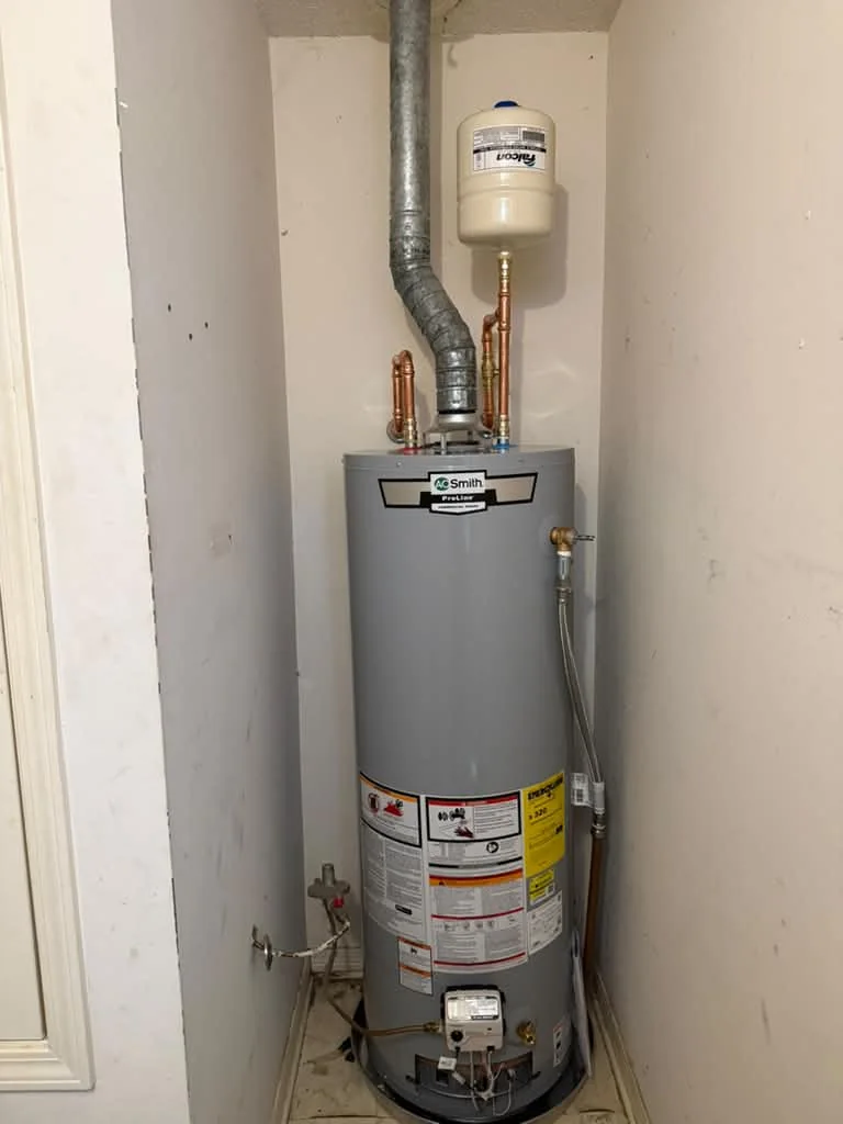 A gas water heater in a narrow closet with a galvanized flue, expansion tank and copper lines