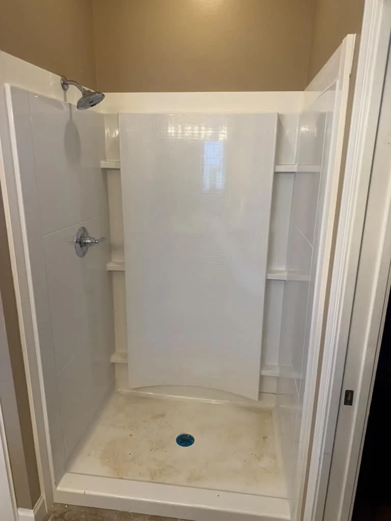 A finished white shower surround with chrome valve trim and built-in shelves
